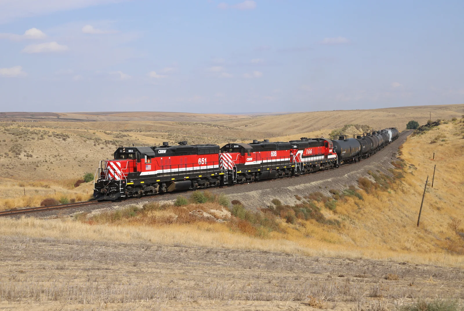 Red Columbia Basin Railroad locomotives pulling freight through rolling open country.